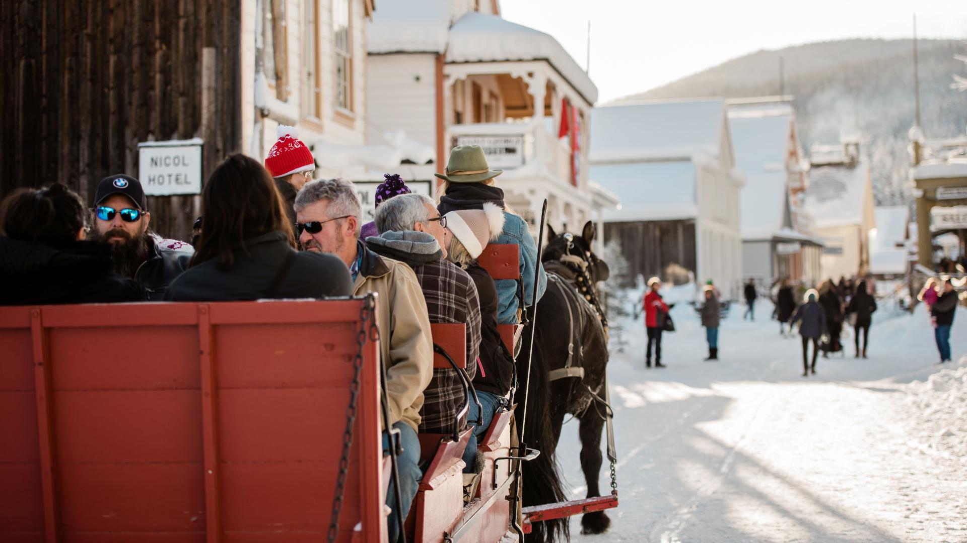 A group of people take a horse-drawn sleigh ride through Barkerville in winter