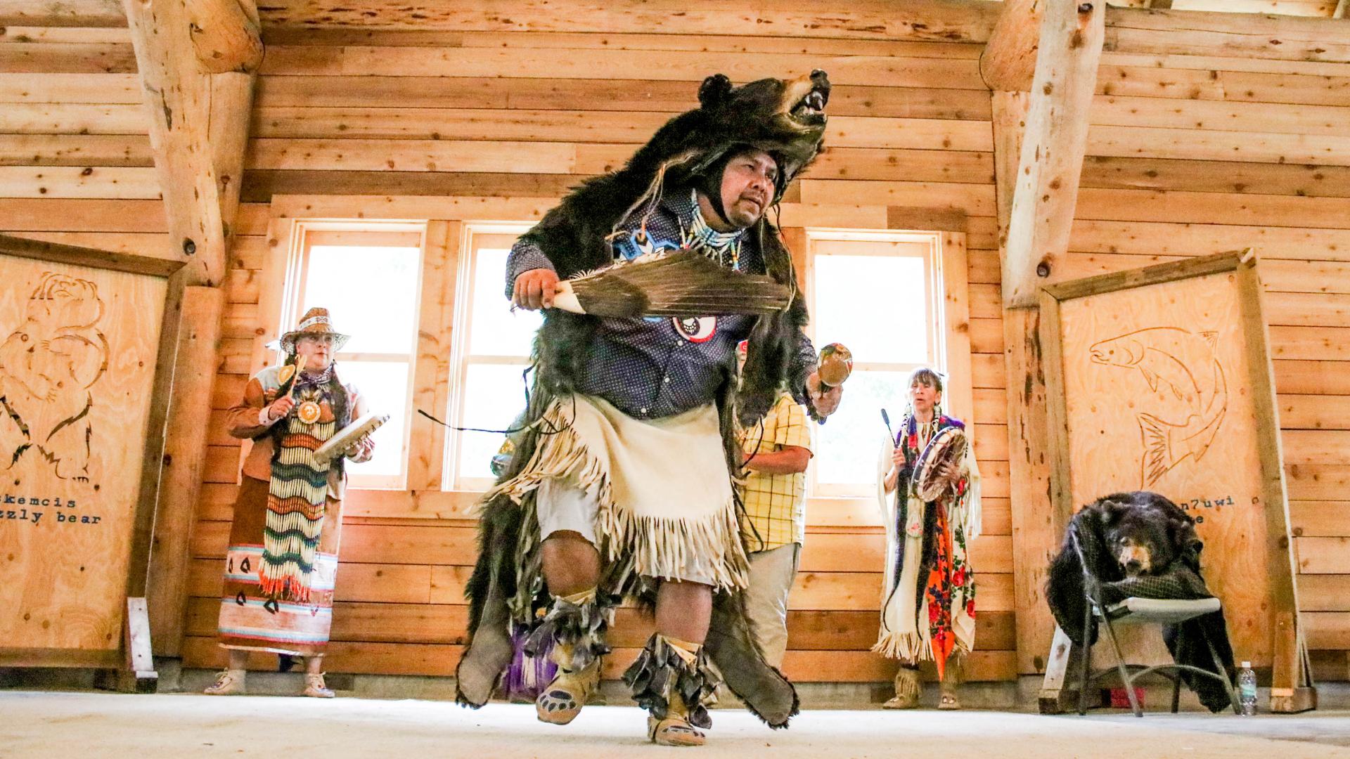 A man in traditional clothing and a bear skin dances at Barkerville's Indigenous People's Day