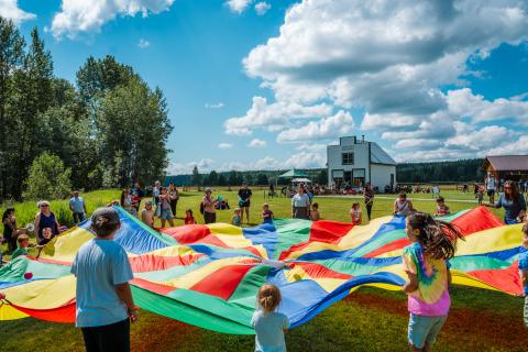 Kids playing with a parachute outside of Huble Homestead